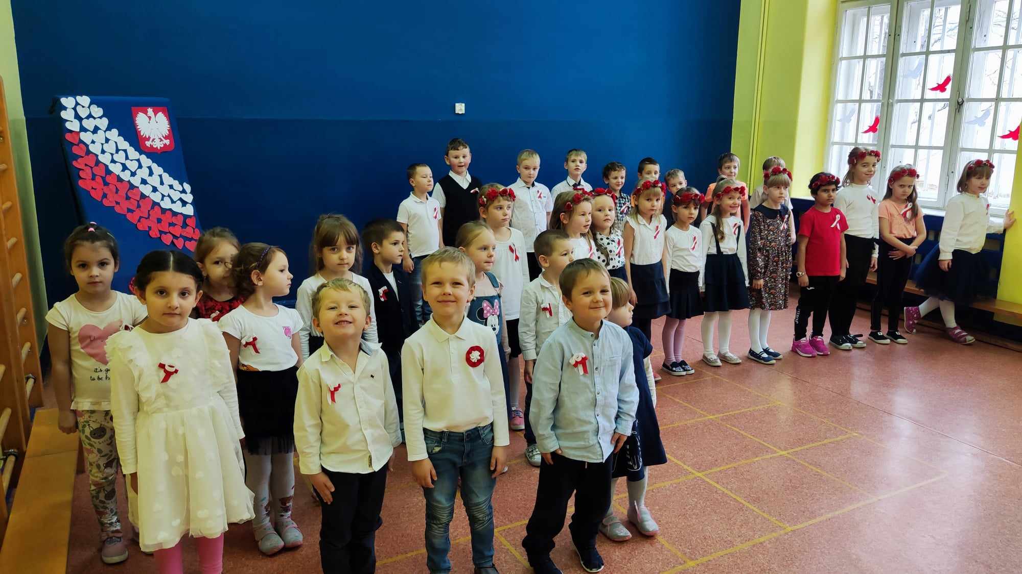 Dzieci ubrane na galowo śpiewają hymn państwowy