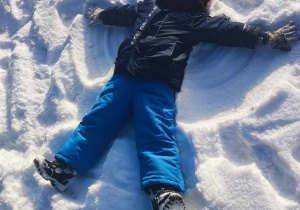 Dziecko robi aniołka na śniegu.