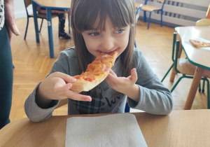 Dziewczynka je pizzę.