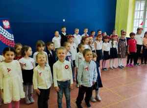 Odświętnie ubrane dzieci śpiewają hymn państwowy.